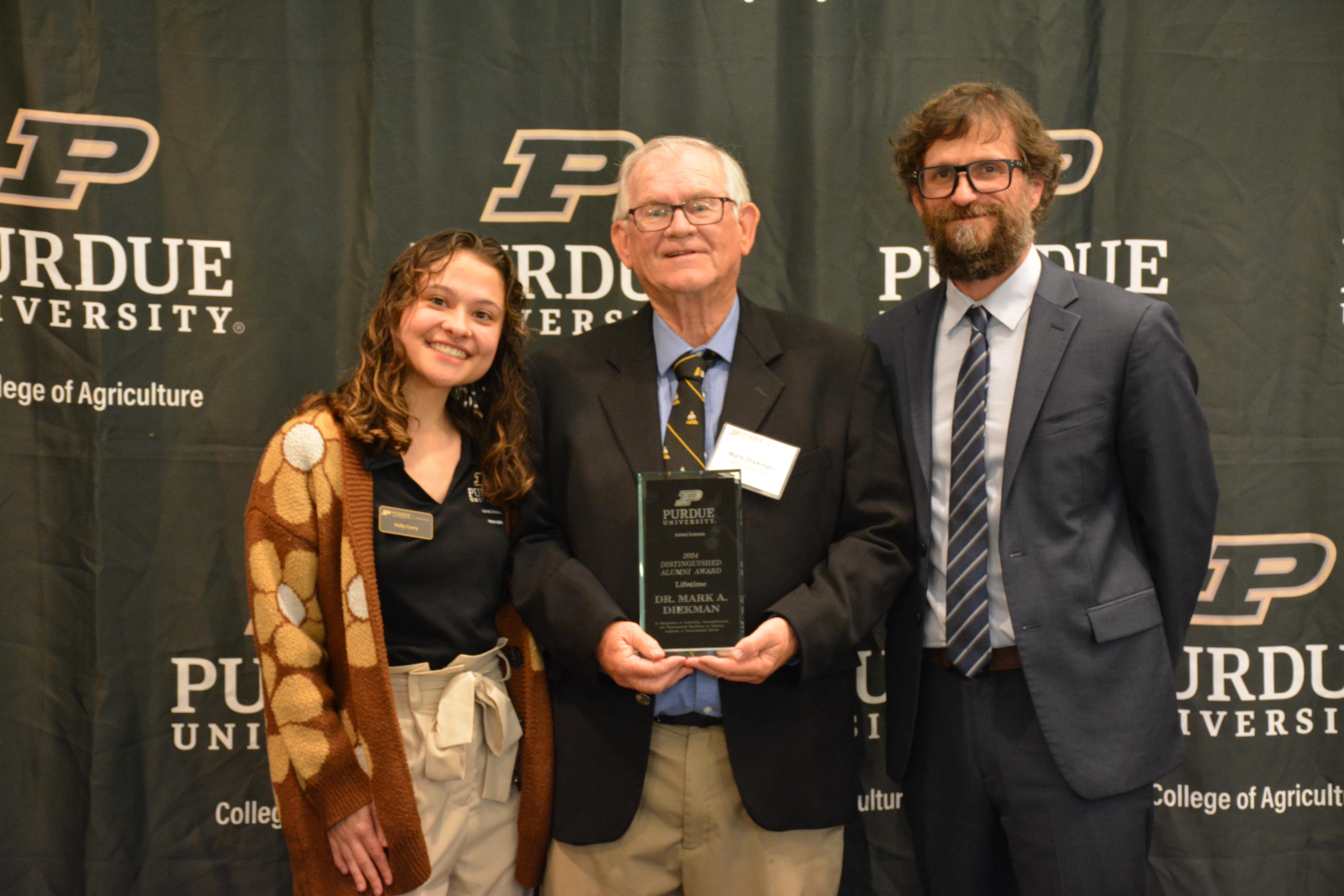 Dr. Mark Diekman accepting award. Dr. Paul Ebner and Kelly Curry stand next to him.