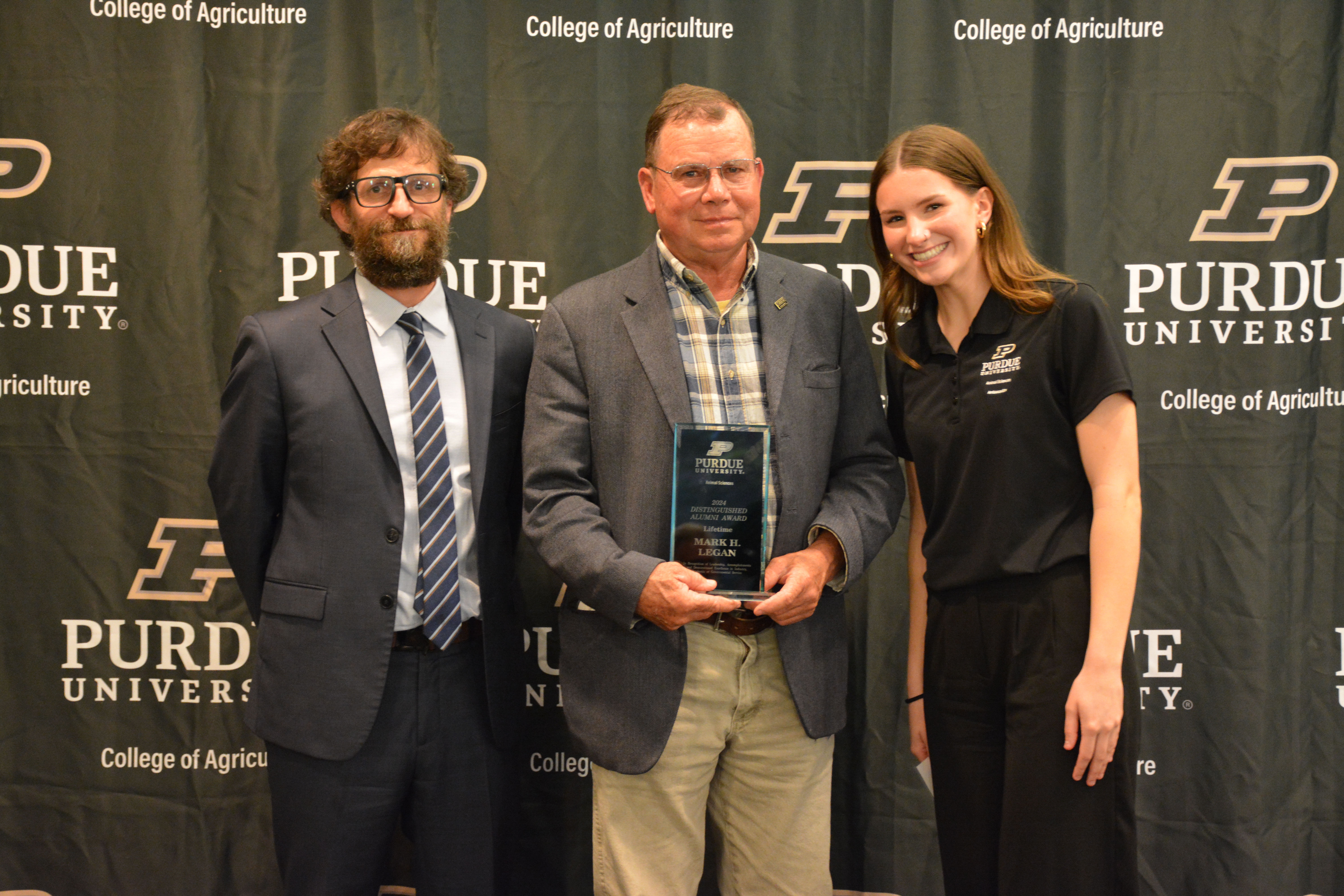 Mark Legan accepting his award. Dr. Paul Ebner and Hadley James stand next to him.