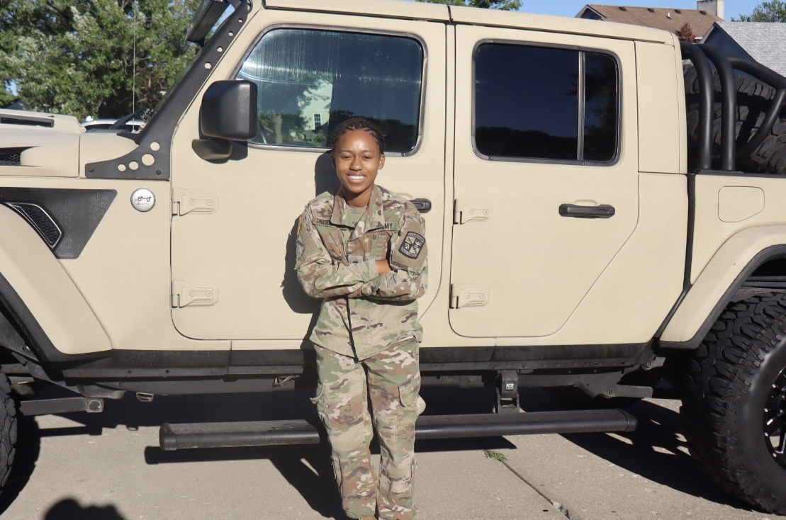 female in military uniform standing in front of a vehicle