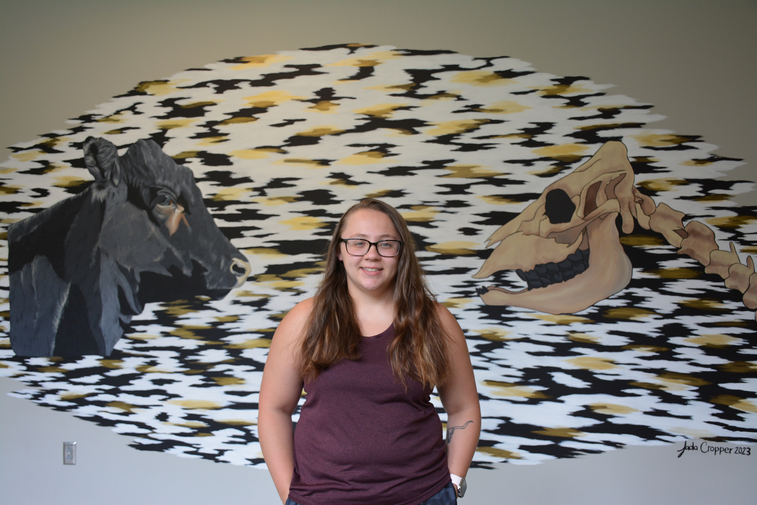 a girl in front of a mural of a cow and a skeleton