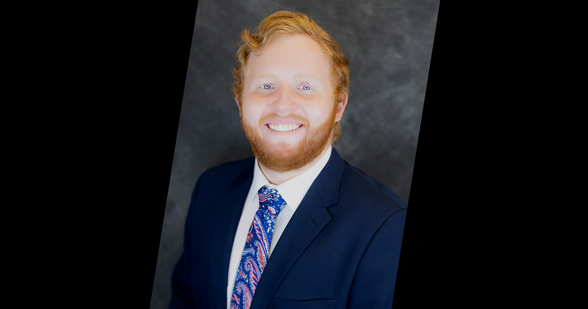 a male in a suit smiling