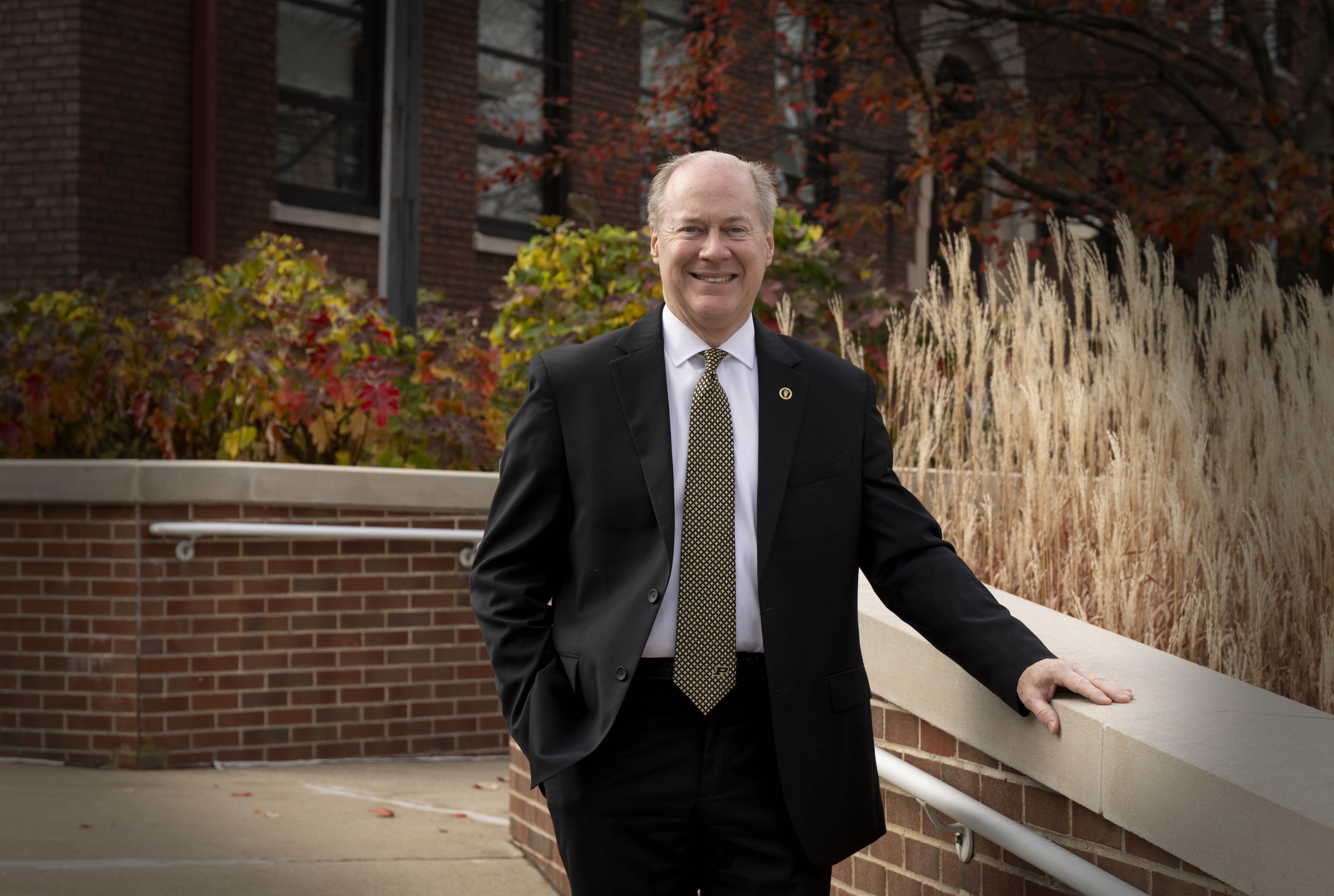 a man smiling in front of a building