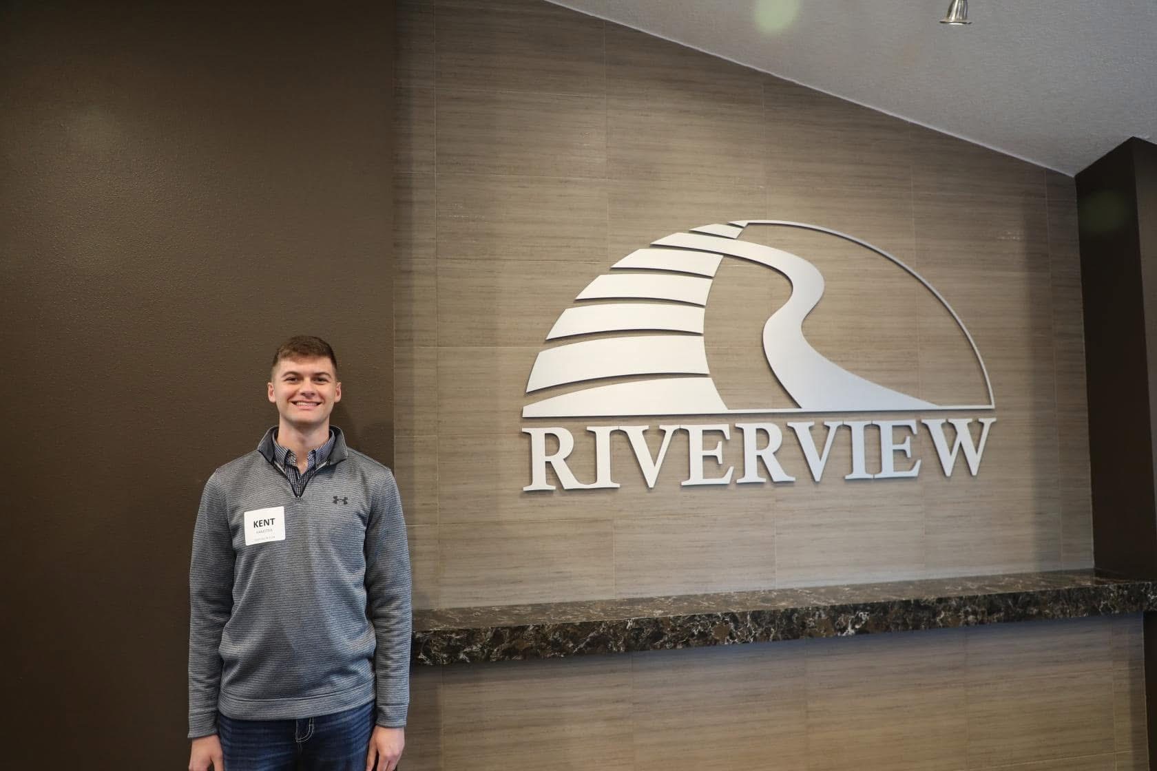 a man standing by a "Riverview" sign