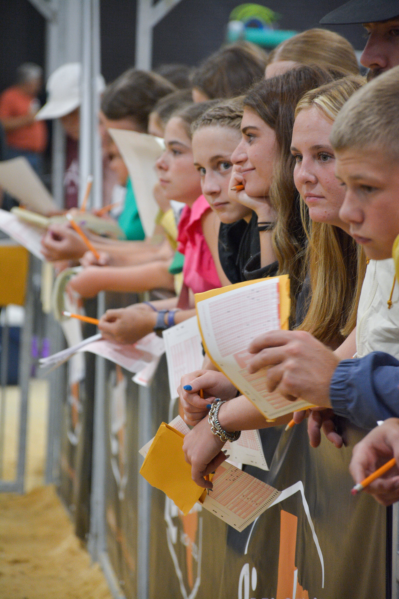 Group of people standing in a line, holding papers and pencils, engaged in a writing activity.