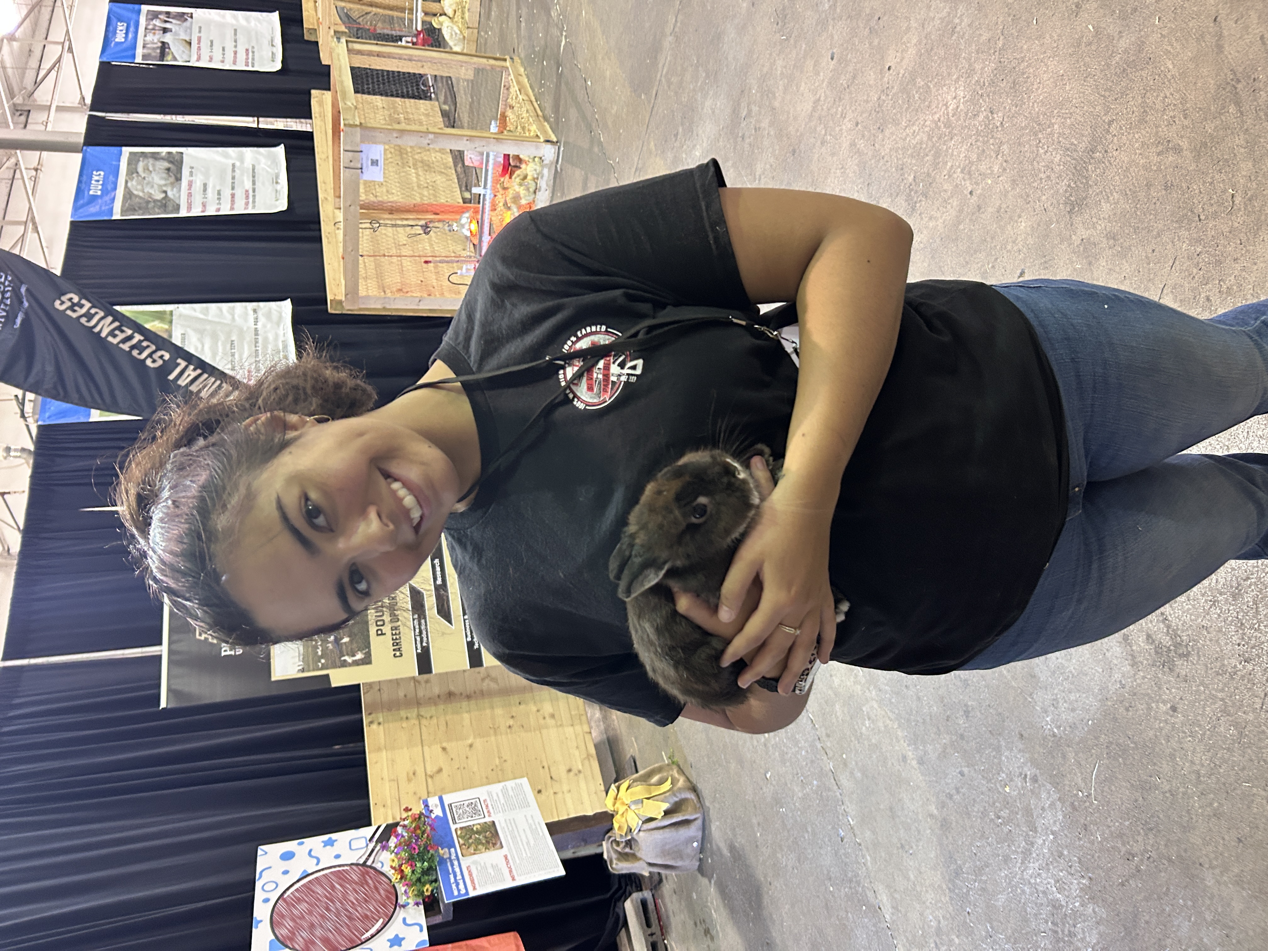 A Purdue Animal Sciences student smiles while holding a rabbit in the Animal Town exhibit at the Indiana State Fair.