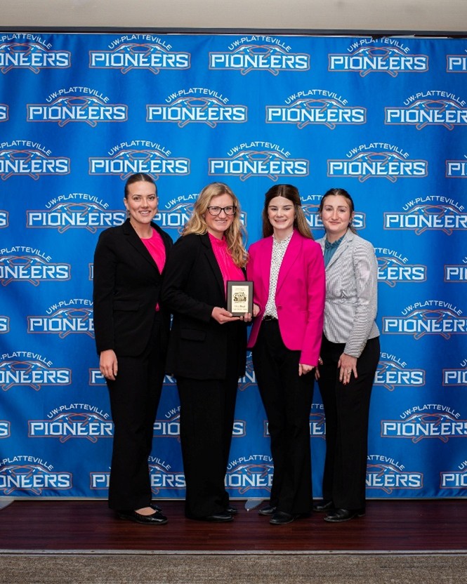 Four Purdue Dairy Club students pose with an award plaque in front of a Pioneer backdrop at the Midwest ADSA meeting.