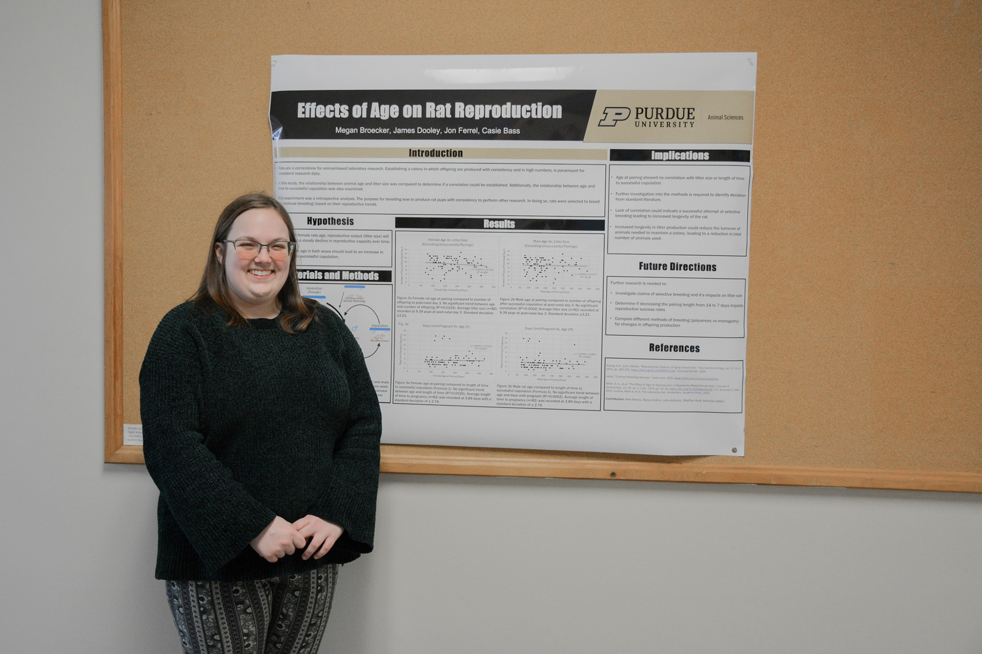 Student stands next to a research poster.