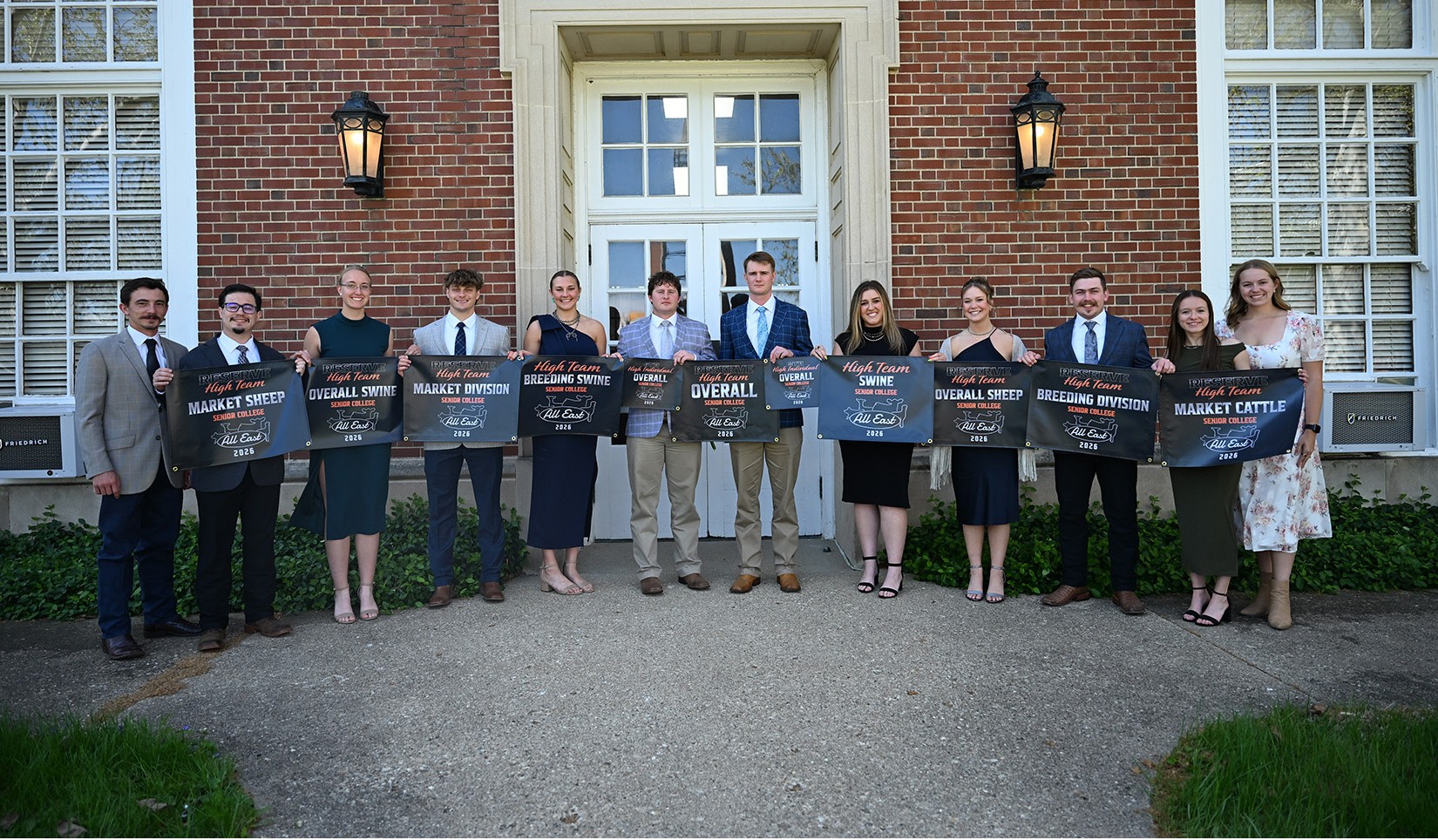 Members and coaches of the Purdue Livestock Judging Team hold banners.
