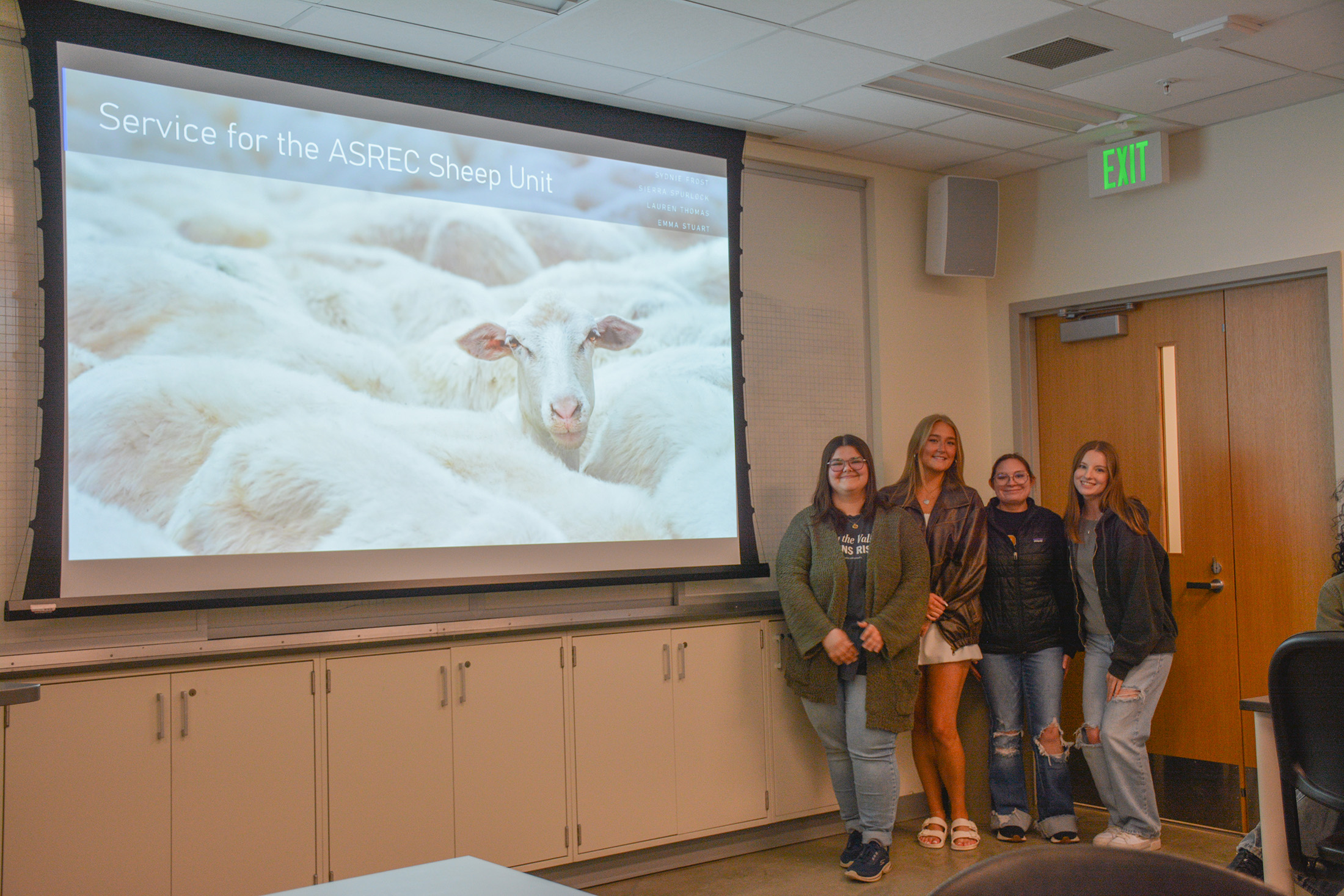Students stand in front of a presentation that's titled "Service for the ASREC Sheep Unit."