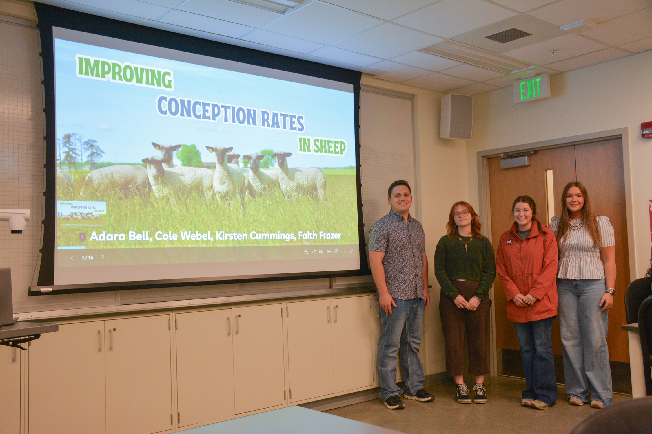 Students stand in front of a presentation that's titled "Improving Conception Rates in Sheep."