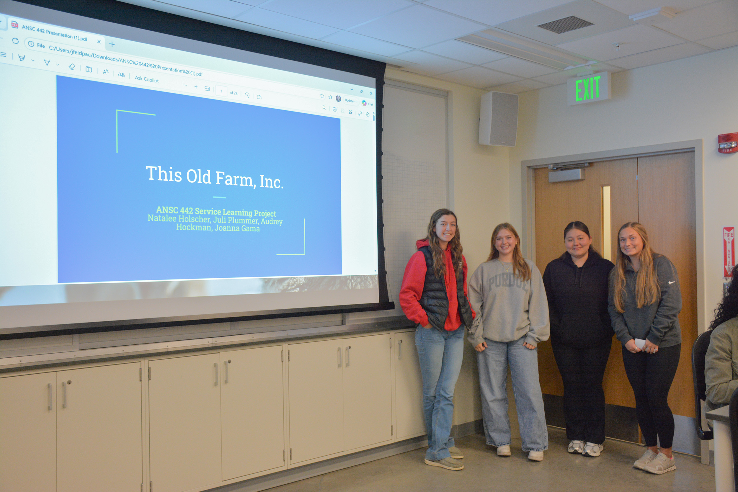 Students stand in front of a presentation titled "This Old Farm, Inc. Service Learning Project."