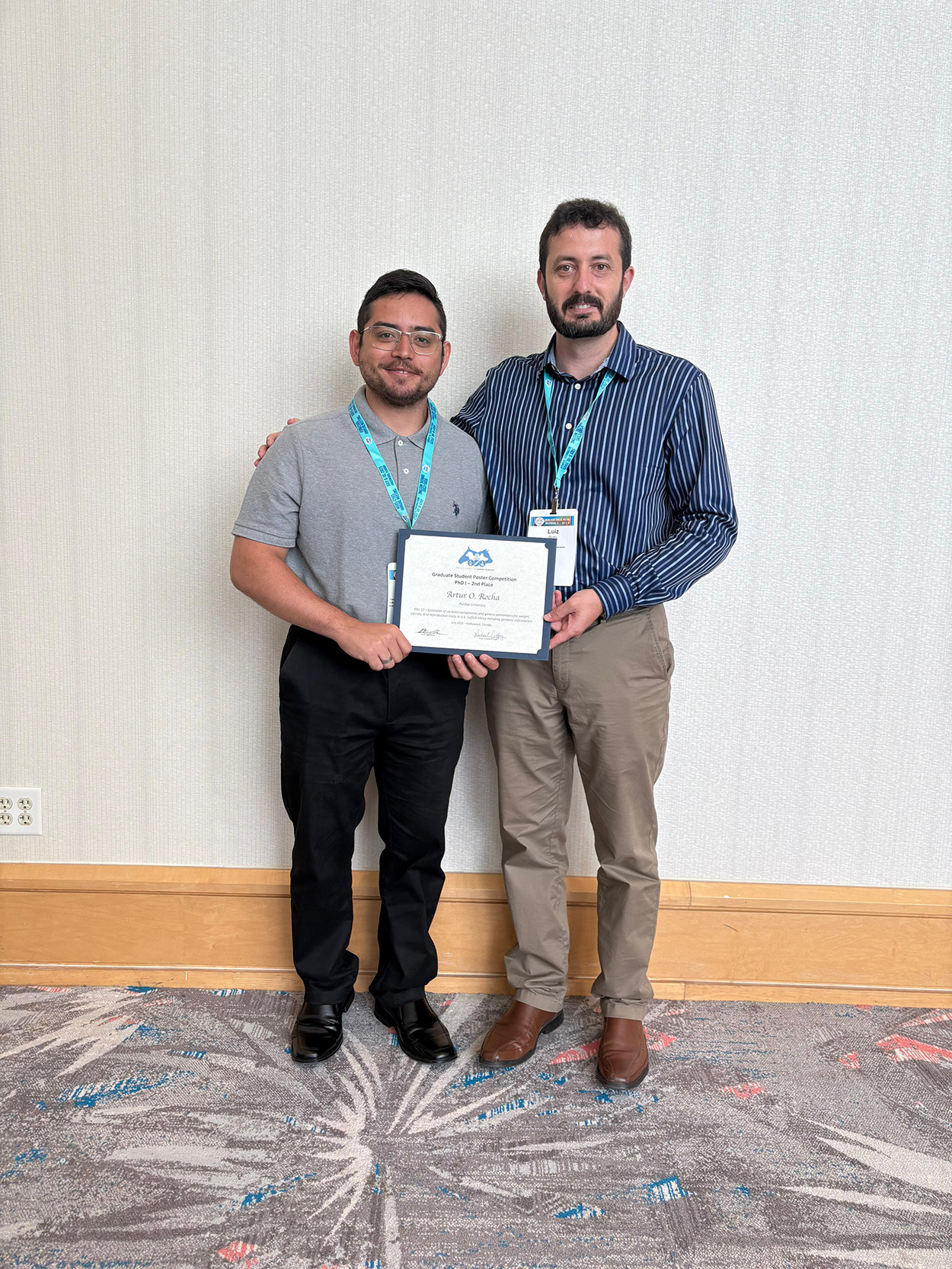 Artur Rocha and Luiz Brito hold an award.
