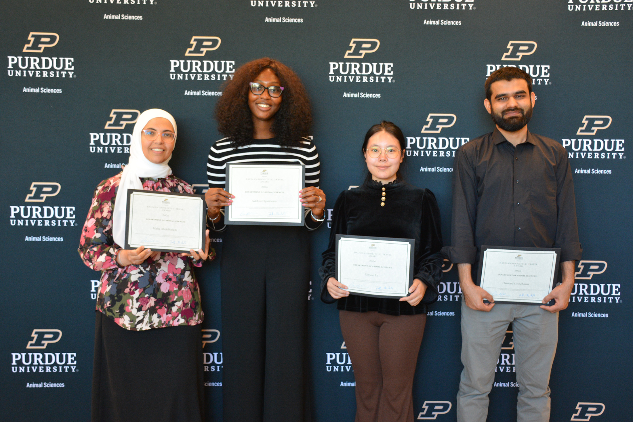 A group of four people stand together holding awards.