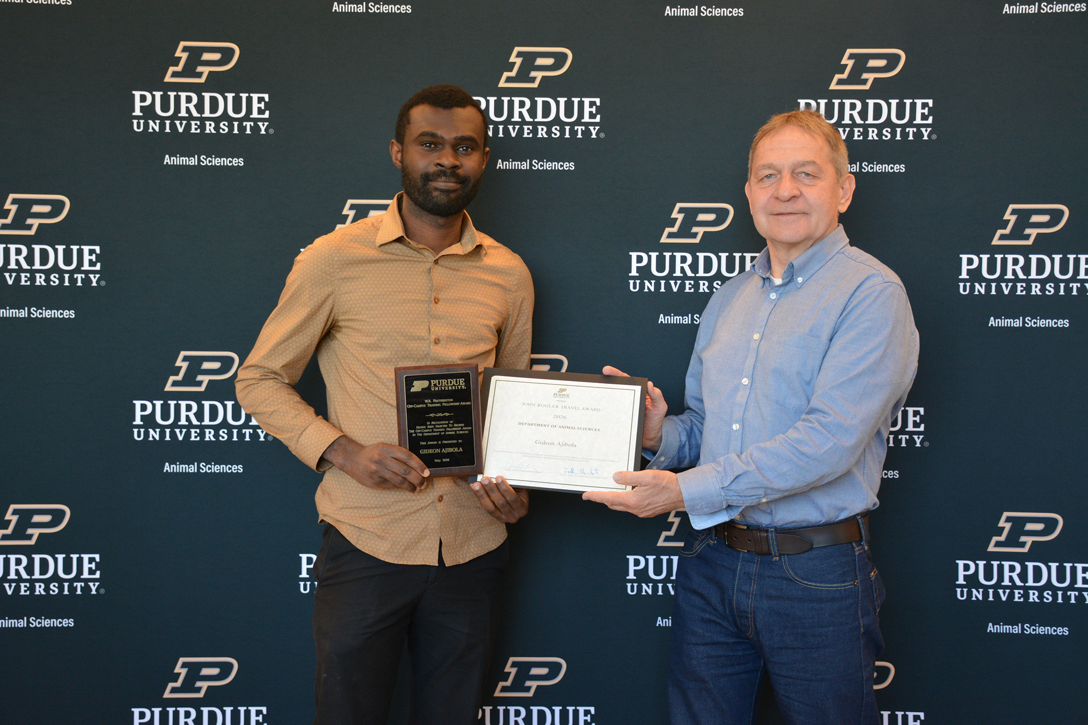 Gideon Ajibola holds a plaque and award with Dr. Zoltan Machaty.