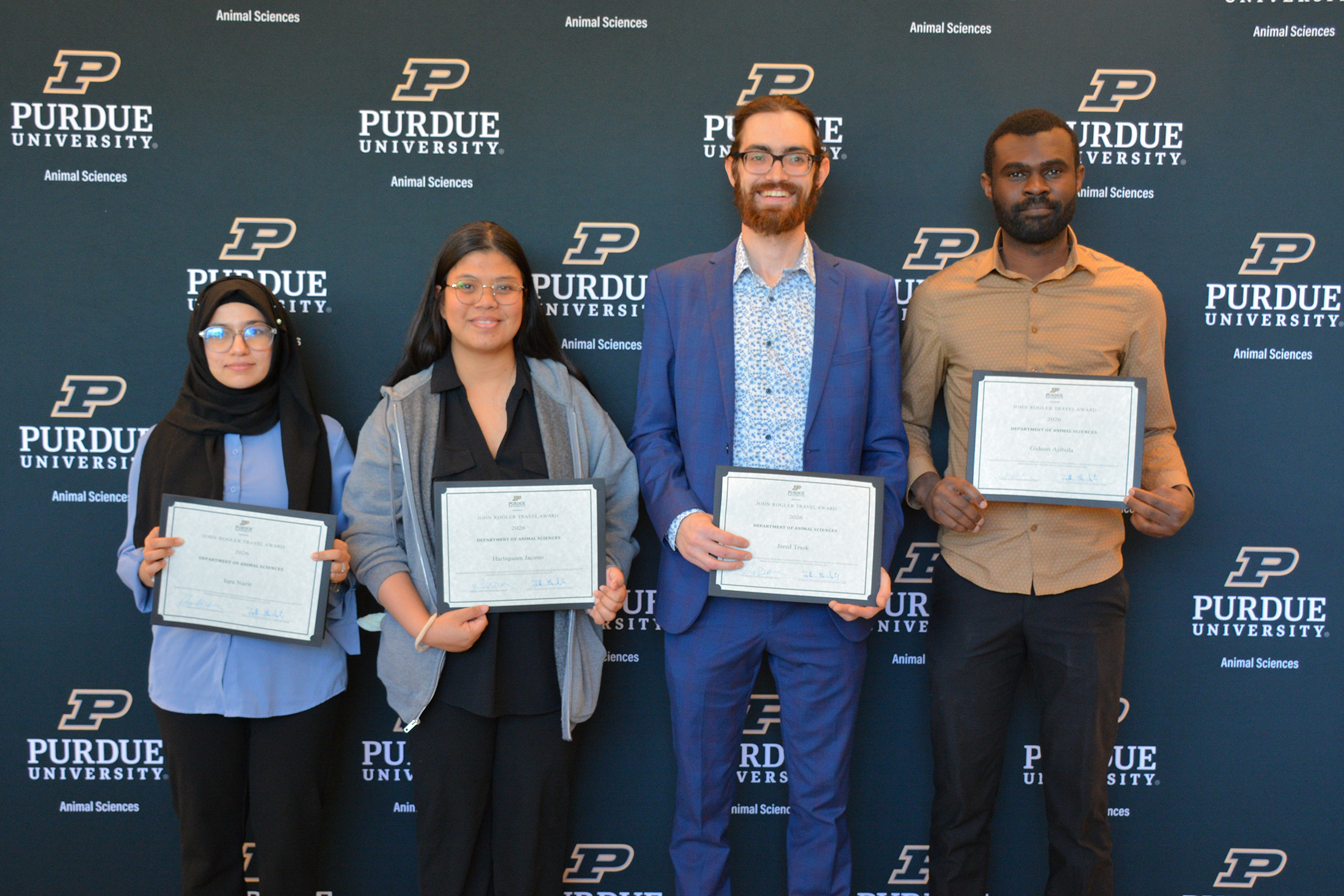 Four people hold awards certificates.