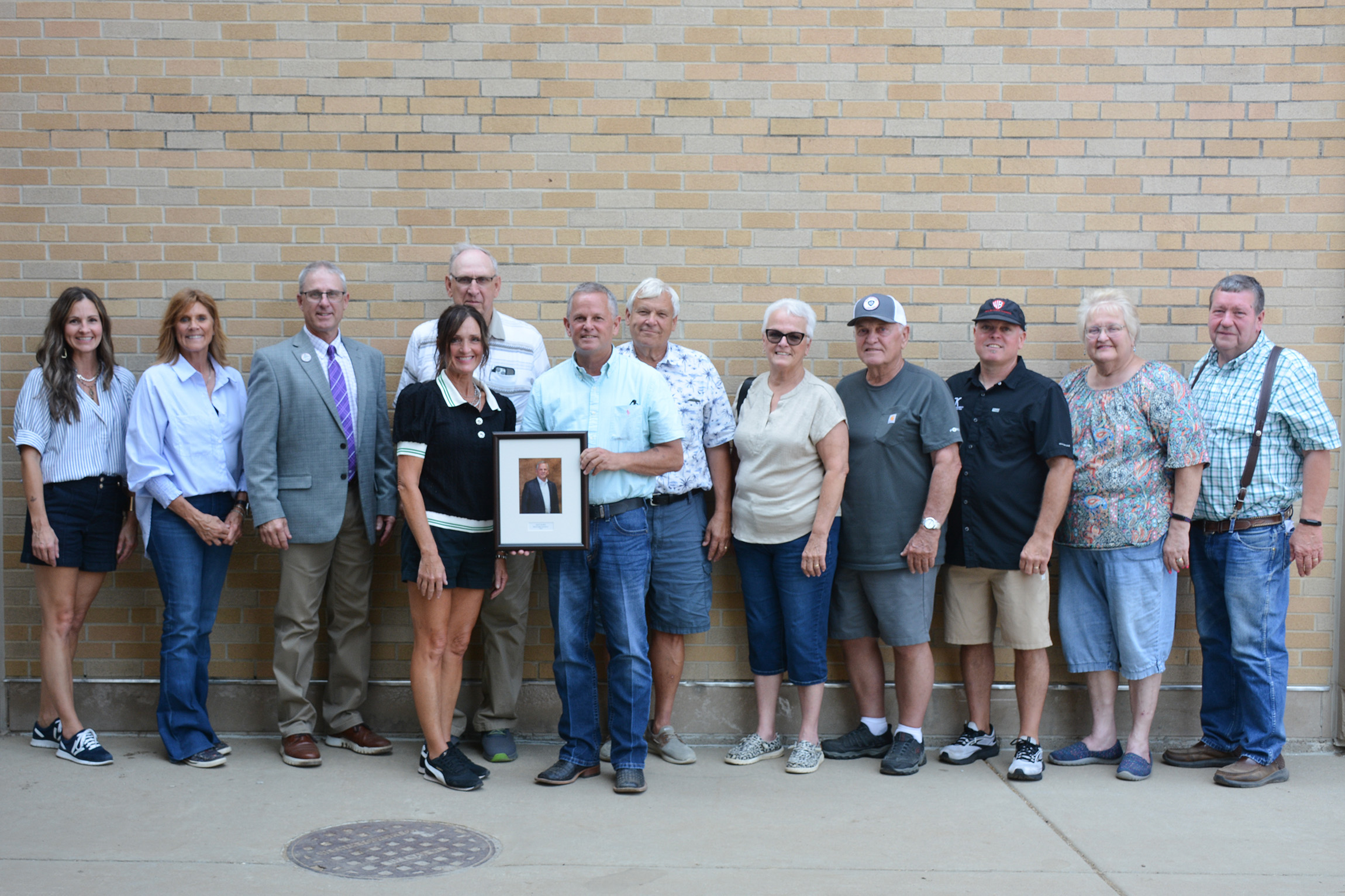Jack Ward and his friends and family stand together in front of a brick wall.