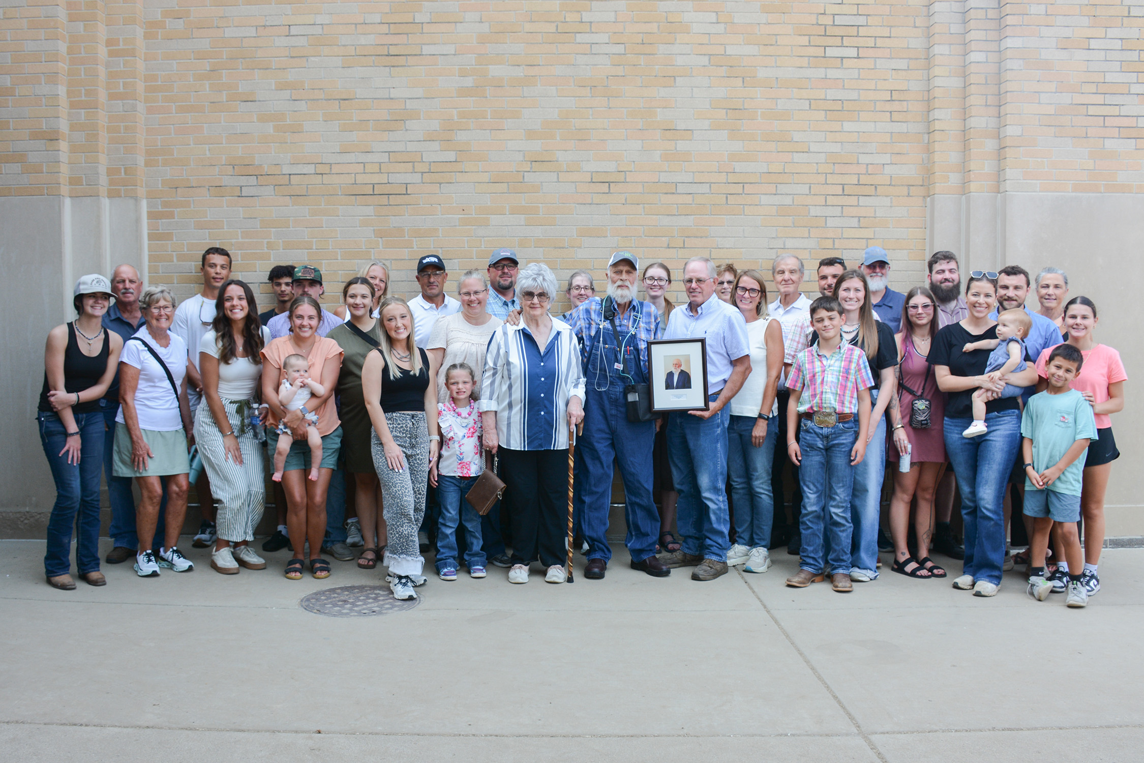 Steve Dahnke and his friends and family stand in front of a brick wall.