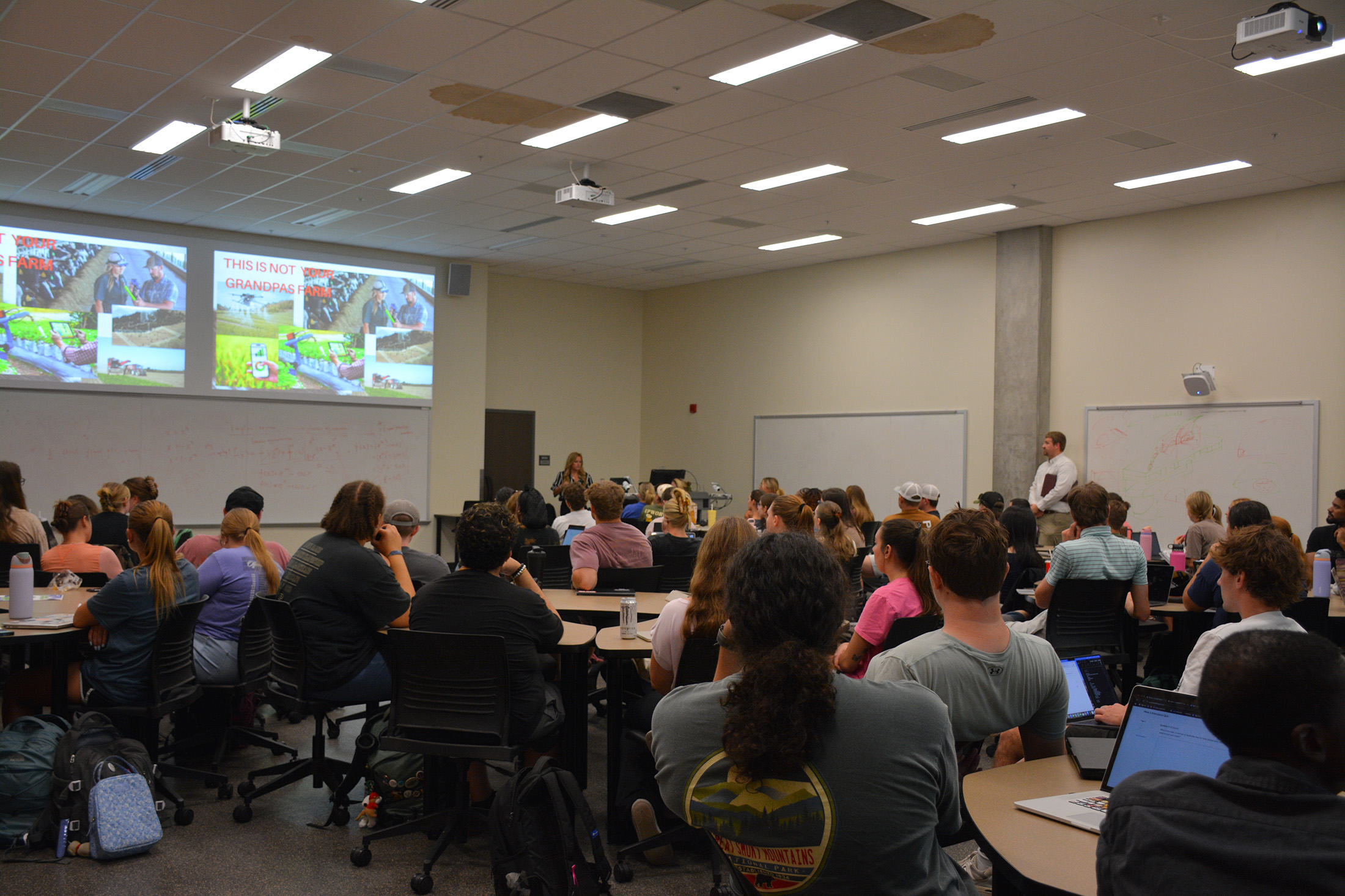 A classroom full of students listens to a presenter.