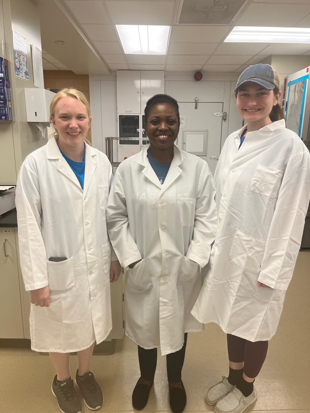 Victoria Uyanga stands with two students in a laboratory.
