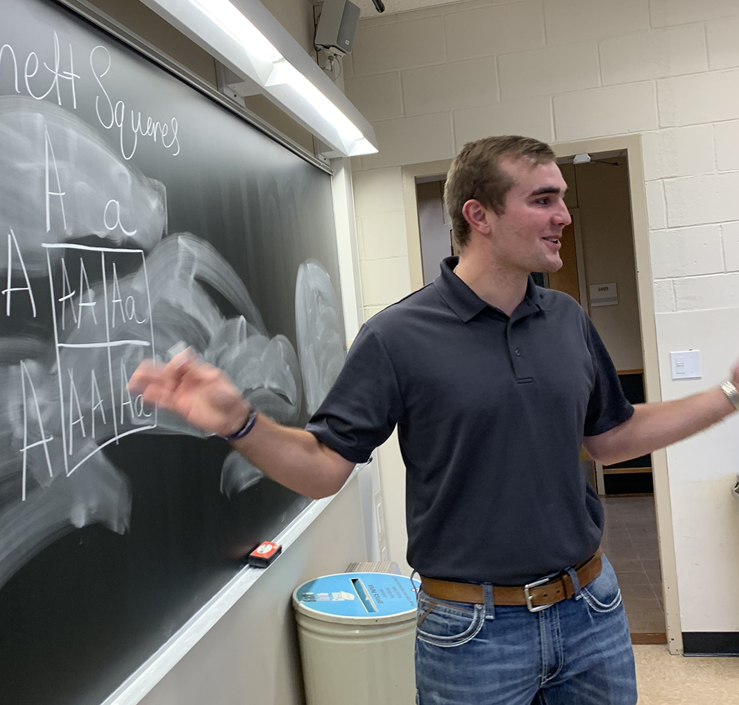 Dillon Muhlenkamp writes on a chalkboard