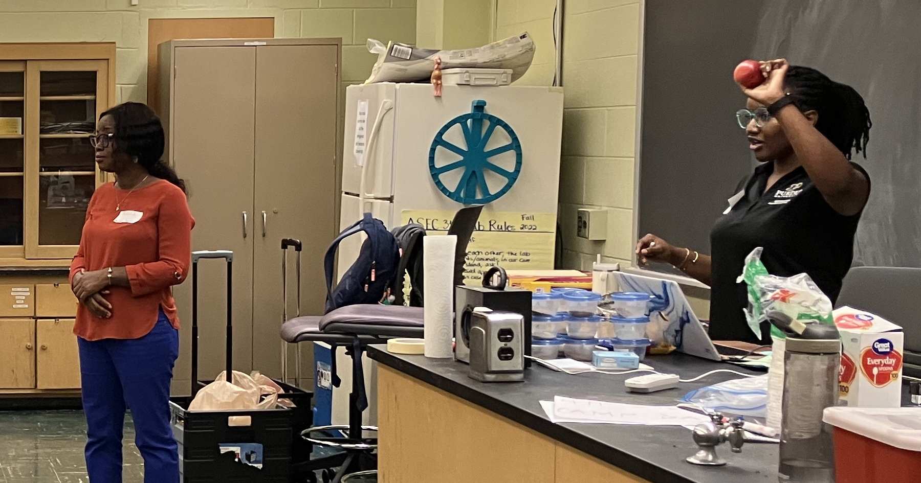 Mavis Akom, ASEC doctoral student, and Favour Ojike, ASEC master’s student, explain the composition of the Earth using an apple during the Soil and Forensic Sciences STEM 4-H Day Camp.