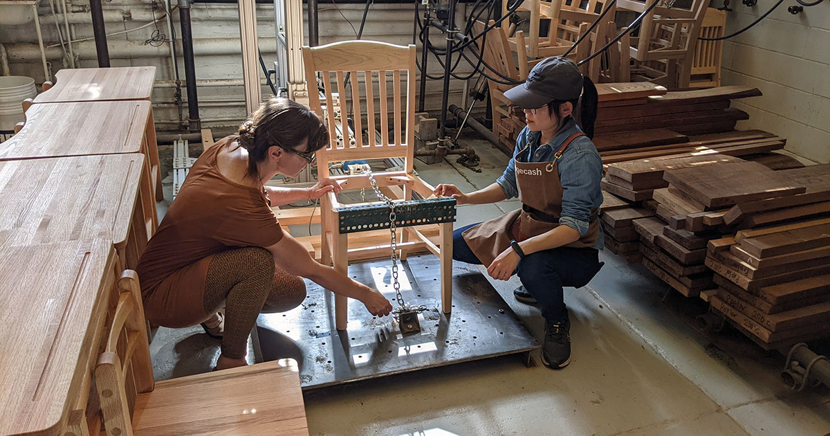 Dr. Eva Haviarova tests a chair's strength with the help of graduate student Ting-Ho Tsai 