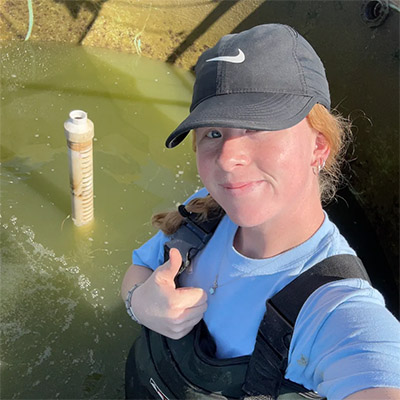 Katie standing in one of the outdoor tanks while harvesting largemouth bass from the 2-year study the ARL has participated in.