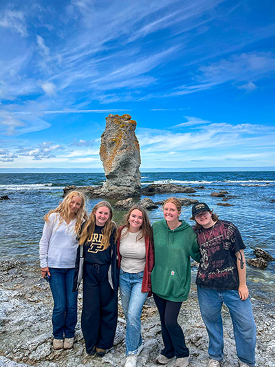 Bella Hilaski and friends stand with a rauk, or limestone seastack at Digerhuvud Nature Preserve.