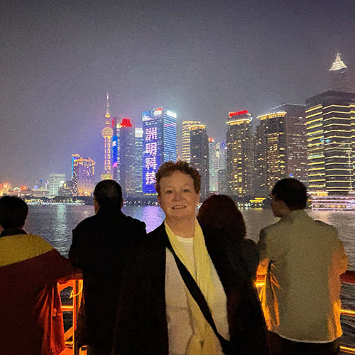 Mary Beth Adams stands in front of a sign publicizing her visit to Nanjing Normal University in China.