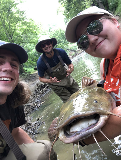 Kirsten Adams with colleagues and a fish they caught during her summer internship at IDEM.