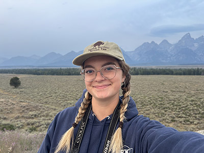 Gloria Aichinger stands in front of a mountain landscape