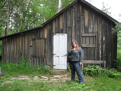 Geriann Albers stands next to a cabin