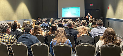 Geriann Albers presenting in front of a large crowd