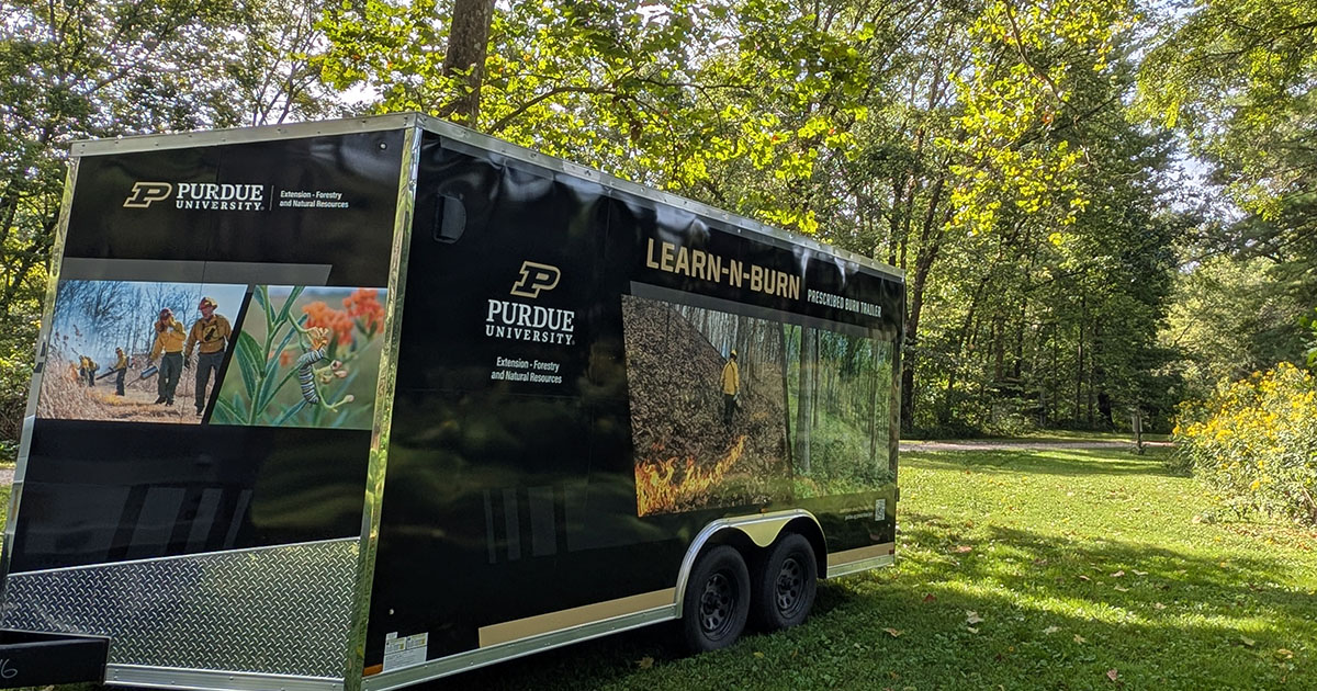 An image of the Learn-N-Burn trailer in front of a forested area at Martell Forest
