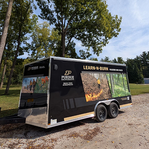 An image of the Learn-N-Burn trailer in front of a forested area at Martell Forest
