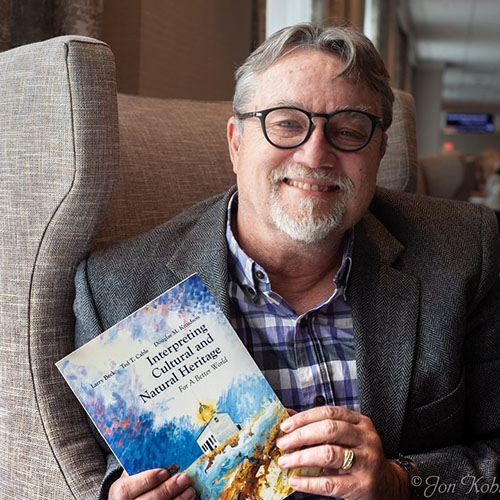 Dr. Ted Cable holds a raccoon in his younger years; Cable visits the Taj Mahal in India while working at Kansas State; Cable holds his book Interpreting Cultural and Natural Heritage for a Better World.
