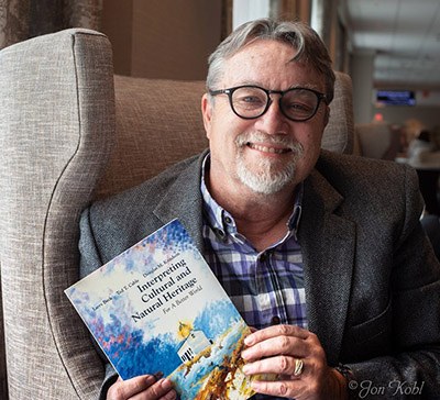 Ted Cable holds a copy of his book "Interpreting Cultural and Natural Heritage"