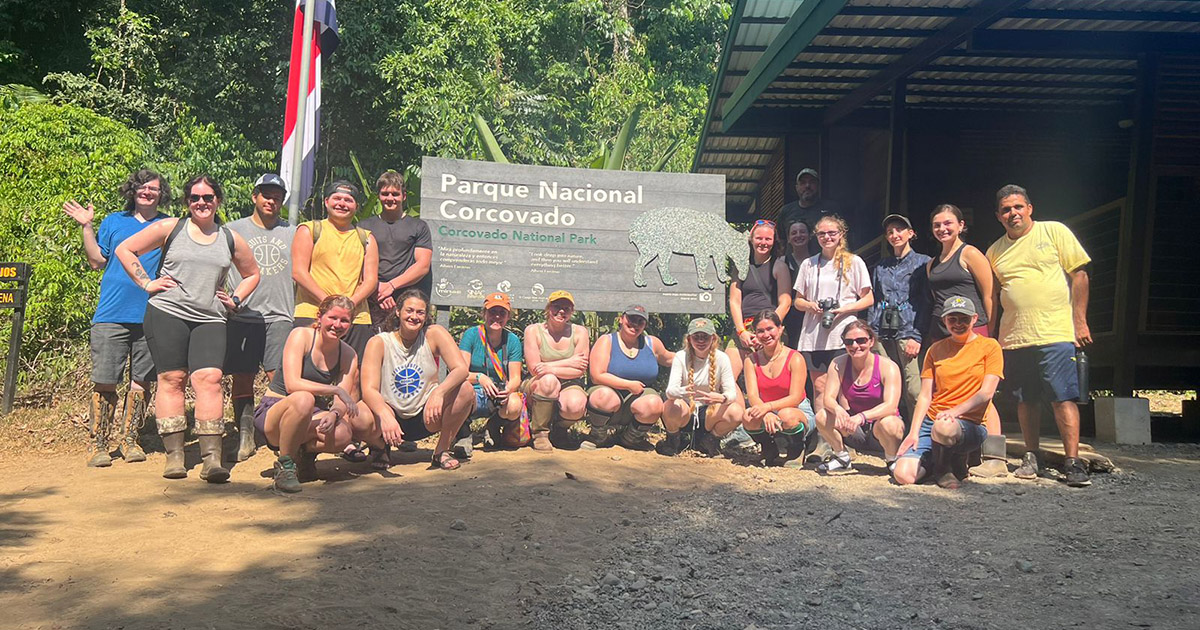 The Costa Rica study abroad group stands next to the entrance sign for Corcovado National Park.