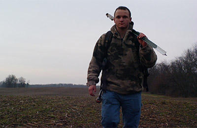 Dr. Zackary Delisle walks through a field while retrieving camara traps during his PhD research.