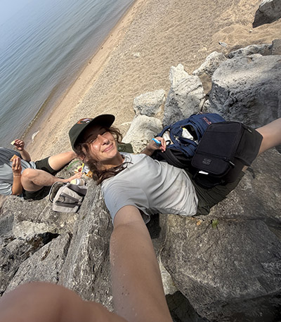 Addy Ellis takes a selfie while sitting on the rocks before a day of sampling at Lake Michigan