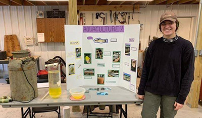 Leah Griffin stands with a display about Aquaculture at Community Nature Day.