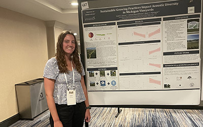 Sarah Grimes stands next to a research poster about her work at Michigan vineyards.