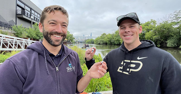 Shedd Aquarium research biologist Austin Happel with Purdue master's student Luke McGill holding acoustic sensors for a fish tracking project