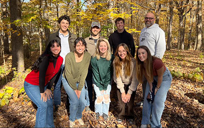 Members of the Purdue Help the Hellbender Lab pose in a forested landscape in November 2023