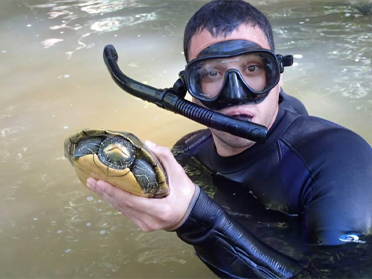 Hernandez-Gomez holding a turtle at a lake