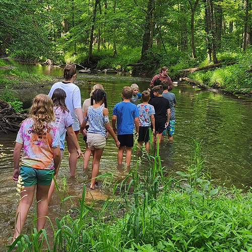 Ava Hoskins paints a pot; Ava leads a group of campers on a walk through the stream.