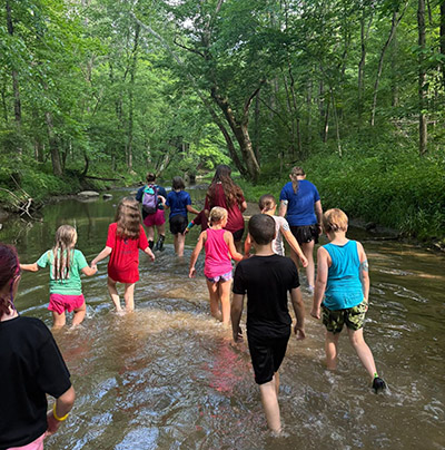 Ava leads campers on a walk through the creek