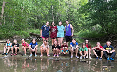 Ava Hoskins with fellow counselors and campers near the creek.