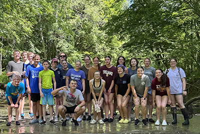 Ava Hoskins with a group of campers near the water.