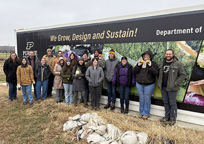The first graduates from the Indiana Land Stewardship Leadership Academy stand together for a group photo in front of Purdue Agriculture trailer.